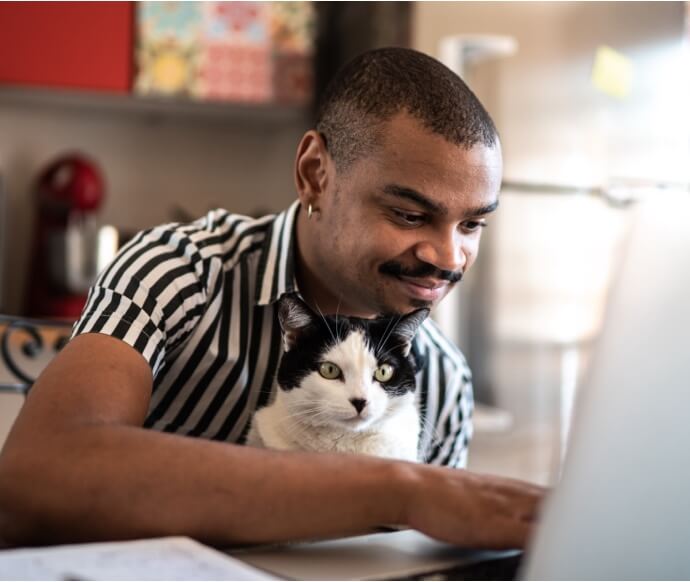 Man using laptop while holding cat